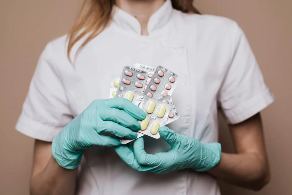 Person med handskar håller tabletter i blisterförpackningar.